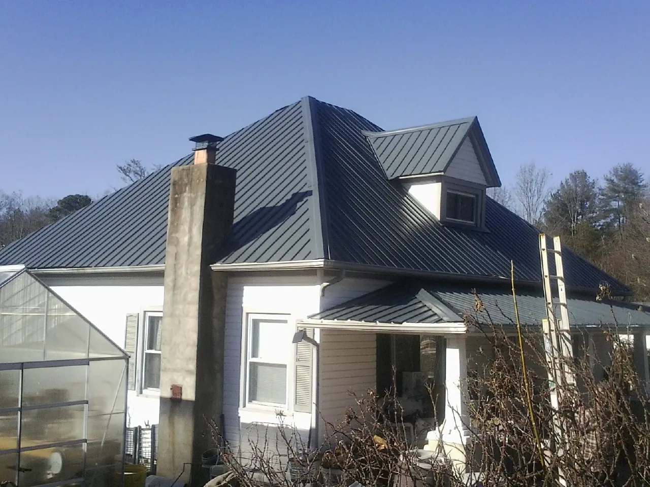 Dark blue standing seam metal roof on a white farmhouse with dormer — Slate & Tile Roof Repair by Roofing Brothers in Elk Grove Village