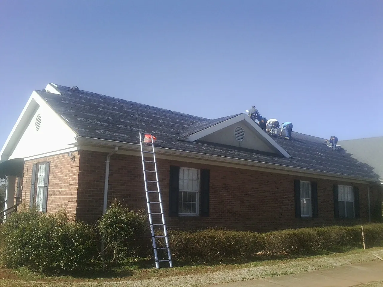 Crew tearing shingles off a brick ranch roof with a ladder set — Metal Roof Repair work by our crew in Elk Grove Village