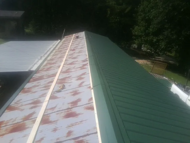 Old rusted panels beside newly installed green metal roofing — Wind Damage Roof Repair by Roofing Brothers in Elk Grove Village