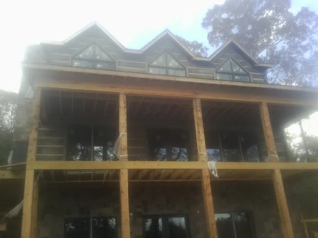 Dormers and porch framing on a large log home under construction — Roof Coating work by our crew in Elk Grove Village