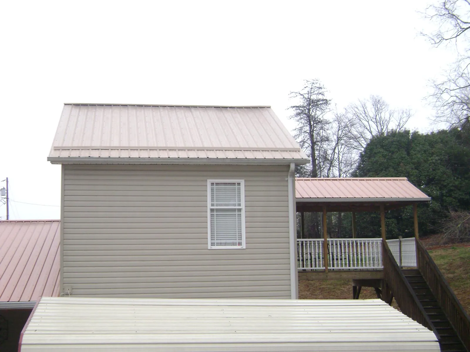 Tan metal roofs on a two story addition and attached porch, from a Roof Replacement job in Elk Grove Village