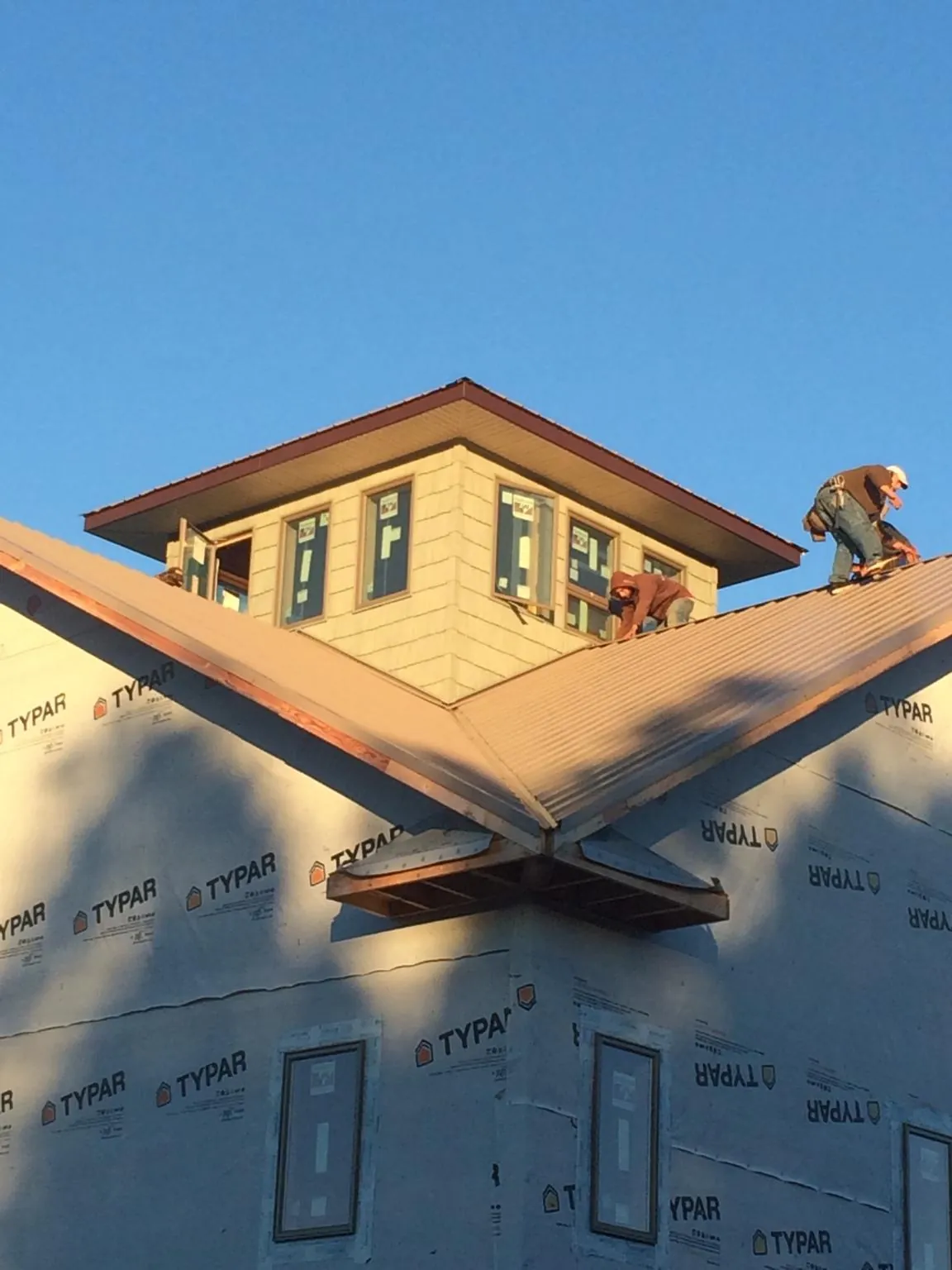 Roofers working around a rooftop cupola on a new metal roof at sunset — Roof Waterproofing in Elk Grove Village by Roofing Brothers
